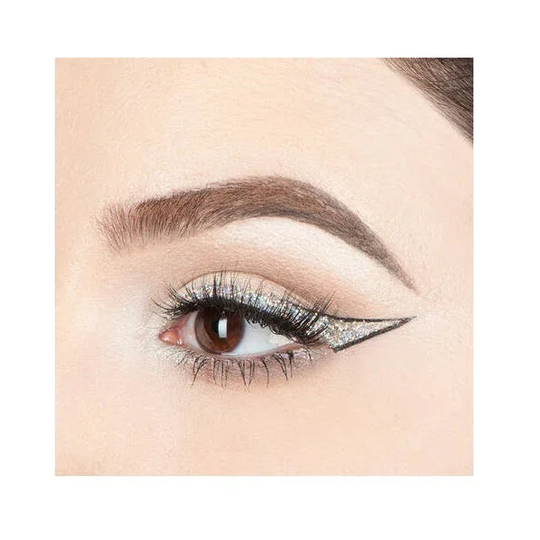 Close-up of eye with glittery winged eyeliner and bold brows, dramatic makeup look