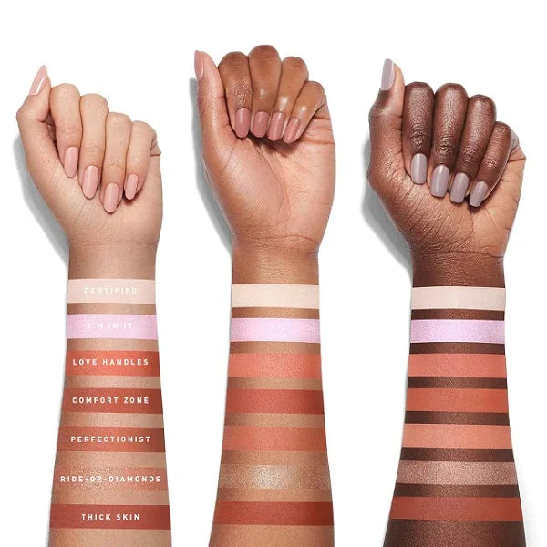 Swatches of various nude and pink eyeshadow shades on three arms with different skin tones.