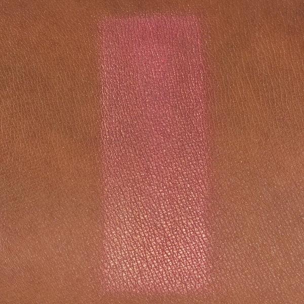 Shimmery pink blush swatch on medium to deep skin tone