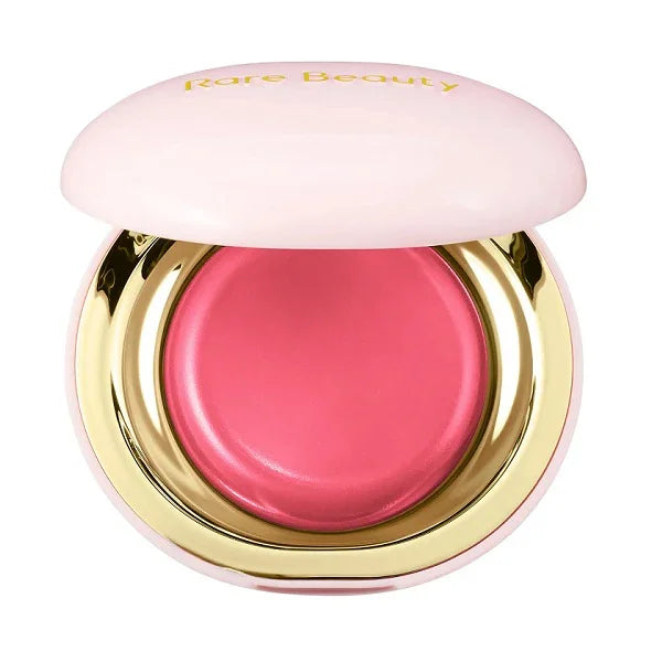 Open compact with pink cream blush and gold trim, lid reads 'Rare Beauty'.