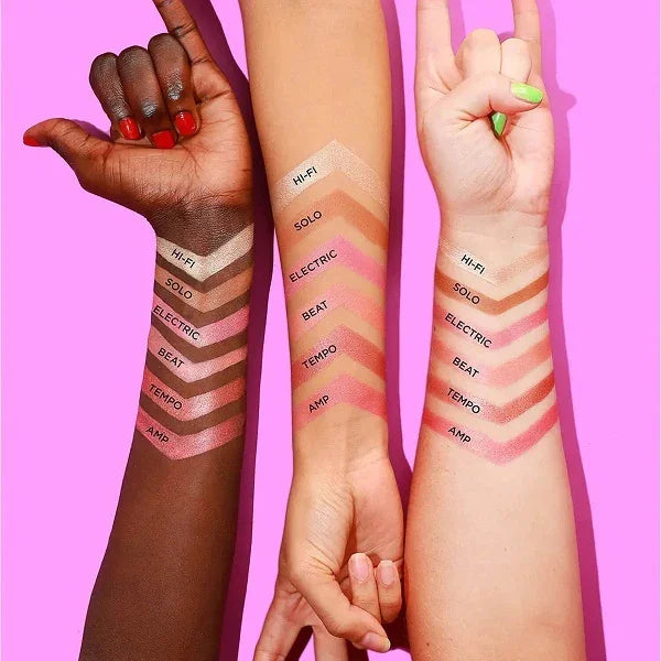 Three arms with different skin tones showing swatches of blush and highlighter shades on a pink background